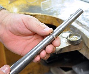 Norman-Hege-Jewelers-ring-sizing-gauge Norman Hege Jewelers | A pair of hands holding a ring sizing gauge with a gold ring on it